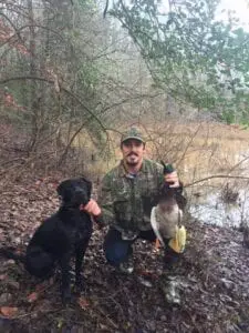 A hunter with its hunting dog and game meat
