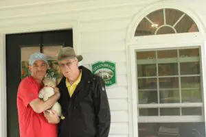An old man with another man holding a puppy