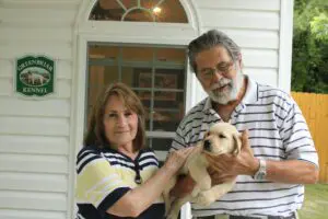 An old man with his wife holding a small puppy